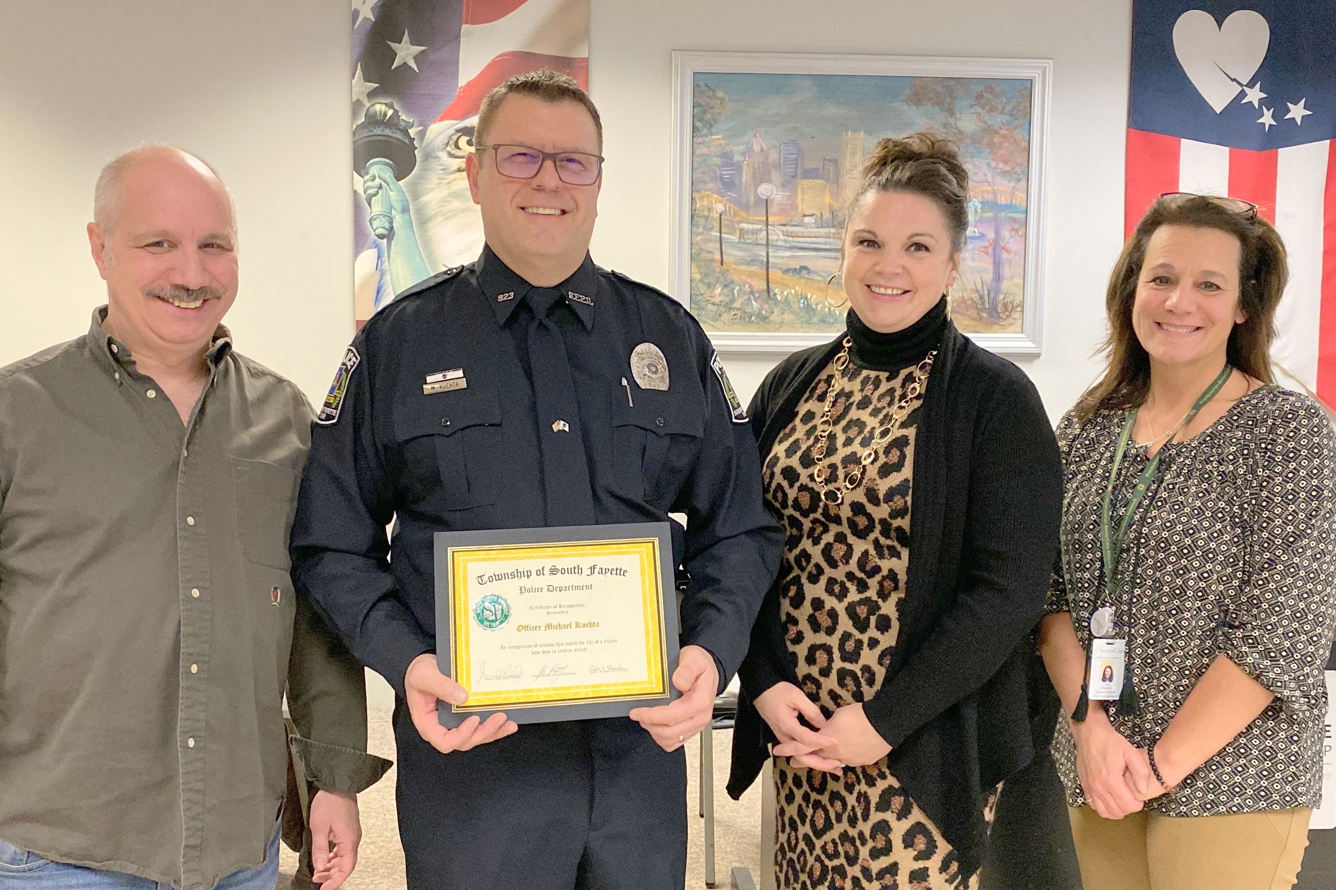 Officer Mike Kuchta holding certificate with three commissioners