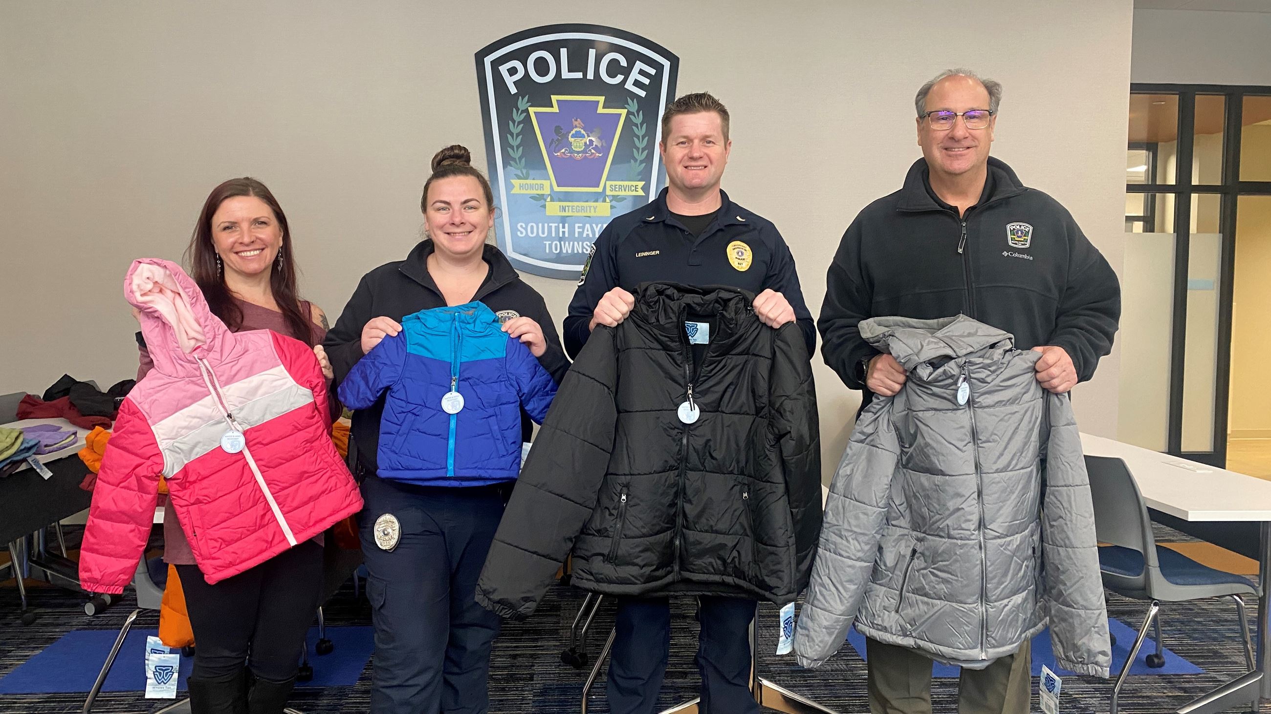 Police officers holding winter coats to donate 2025 